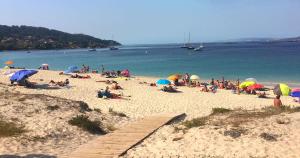 a group of people on a beach with umbrellas at PAUTANA, céntrico y a pocos minutos de Vigo in Cangas de Morrazo