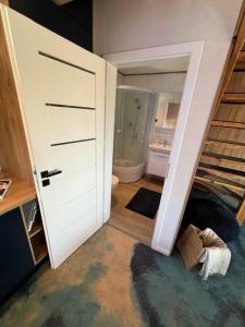 um quarto com uma porta que leva a uma casa de banho em GooseHaus em Gąski