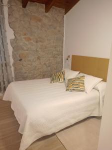 a bed in a room with a stone wall at Casuca Rubia in Bosquemado
