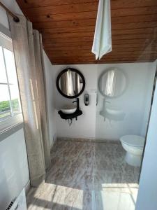 a bathroom with a toilet and two mirrors at Aloxamento A Mariña in Oia