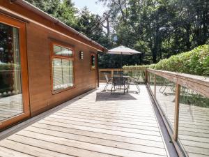 a wooden deck with a table and an umbrella at Swinsty Lodge in Harrogate