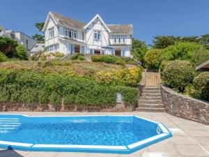 una casa con una piscina azul frente a una casa en Windy Heath en Salcombe