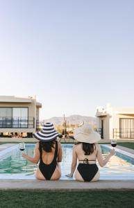 Dos mujeres en bikini sentadas junto a una piscina en Sol del Valle en Valle de Guadalupe