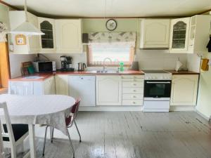 uma cozinha com armários brancos, uma mesa e um lavatório em Old vacation house em Skjåk