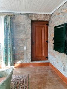 a room with a wooden door and a tv on a stone wall at ROSAS DA GRANJA - CASA DE CAMPO in Granja