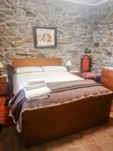 een slaapkamer met een bed en een stenen muur bij ROSAS DA GRANJA - CASA DE CAMPO in Granja