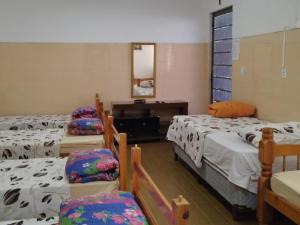 Cette chambre comprend 4 lits avec des chaises et un piano. dans l'établissement POUSADA MONTE HOREB, à Cachoeira Paulista