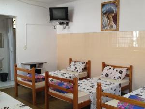 a room with three beds and a tv on the wall at POUSADA MONTE HOREB in Cachoeira Paulista