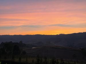 a sunset over a hill with a field and trees at Misty English Cottage in Ban Non Na Yao