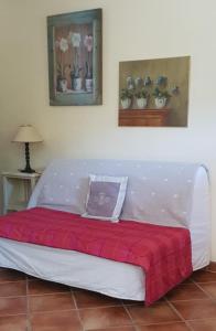 a white bed with a red blanket on top of it at La Maison Verte in Tulette