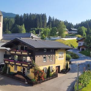 a yellow house with a black roof on a street at Pension Haus Rohrmoser in Annaberg im Lammertal