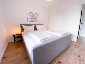 a bed with white sheets and pillows in a room at Apartment mit Rheinblick, Messe, Balkon, Küche, Parkplatz in Neuss
