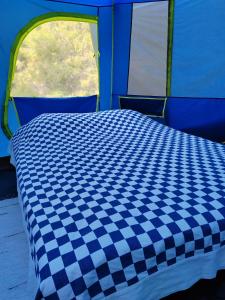 a blue and white checkered bed in a tent at Puumaja maaseudulla in Tuorila