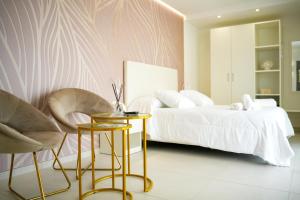a bedroom with a bed and two chairs and a table at Sirena Suite Deluxe in Peschici