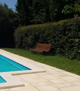 a wooden bench sitting next to a swimming pool at La Maison Verte in Tulette
