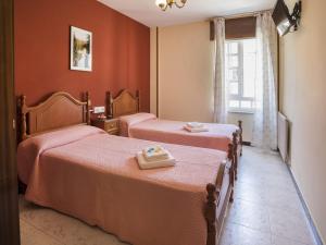 2 Betten in einem Zimmer mit roten Wänden und einem Fenster in der Unterkunft Pensión Castro Parrillada in Samos