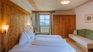 - une chambre avec 2 lits, un canapé et une fenêtre dans l'établissement Ütia De Börz, à San Martino in Badia