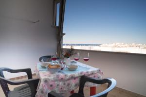 a table with wine glasses and a view of the ocean at Monolocale ilporticciolovacanze in Villanova di Ostuni