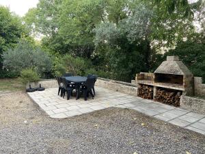 eine Terrasse mit einem Tisch, Stühlen und einem Grill in der Unterkunft coconing et chaleureux T2 in Rochefort-du-Gard