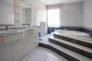 ein weißes Badezimmer mit zwei Waschbecken und einer Badewanne in der Unterkunft Pensión Castro Parrillada in Samos