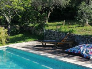 einen Pool mit einer Bank neben einer Steinmauer in der Unterkunft Charmant logement provençal avec piscine à deux pas du village médieval in Seillans