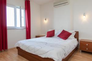 une chambre avec un grand lit avec des oreillers rouges dans l'établissement Apartment natalia, à Podgora