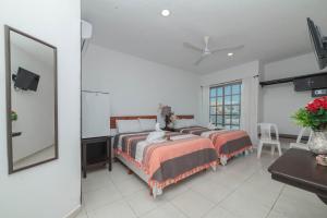 a bedroom with two beds and a table and a tv at Hotel La Trigueña in Isla Mujeres
