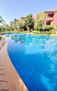 una piscina con acqua blu in un resort di Dar Marrakech a Marrakech