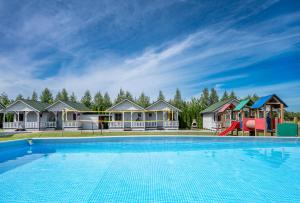 a large swimming pool in front of a row of houses at Domki Bałtyku Szept in Darłowo