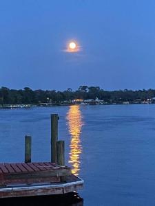 una luna que se eleva sobre un cuerpo de agua con un muelle en Moonlite Retreat- Waterfront home in Welaka, Florida en Welaka