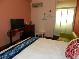 um quarto com uma cama, uma cadeira e uma televisão em Home in Hengchun Homestay em Hengchun Old Town