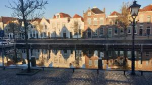 um reflexo de casas na água de um canal em B&B De Grote Kade I Bella Zeelandia em Goes