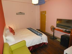 um quarto com uma cama, uma televisão e uma cadeira em Home in Hengchun Homestay em Hengchun Old Town