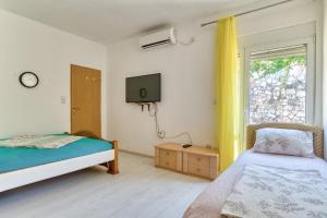 1 dormitorio con 2 camas, TV y ventana en Sara Sutomore, en Sutomore