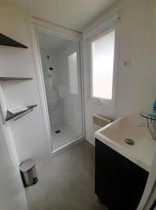 a white bathroom with a shower and a sink at Plage de Contis, Camping SIBLU 3*, parc aquatique, piscines chauffées. in Saint-Julien-en-Born