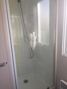 La salle de bains est pourvue d'une douche avec une porte en verre. dans l'établissement Plage de Contis, Camping SIBLU 3*, parc aquatique, piscines chauffées., à Saint-Julien-en-Born