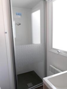 a glass shower in a bathroom with a sink at Plage de Contis, Camping SIBLU 3*, parc aquatique, piscines chauffées. in Saint-Julien-en-Born