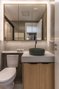 a bathroom with a toilet and a sink with a mirror at Moov 916 Studio Mooca in Sao Paulo