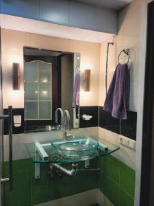 a bathroom with a glass sink and a mirror at City Center Van Gogh Suite in Tbilisi City