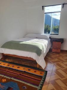 1 dormitorio con 1 cama con ventana y alfombra en Vértigo Valle Sagrado, en Urubamba