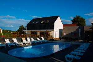 a swimming pool with lounge chairs and a house at Domki Borys in Jastrzębia Góra