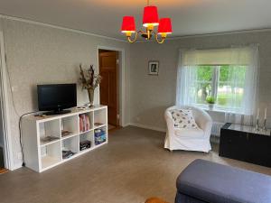 a living room with a tv and a white chair at Flygeln in Strängnäs