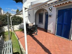 um pátio com uma mesa e cadeiras e portas azuis em Villa Esperanza em Marina di Cerveteri