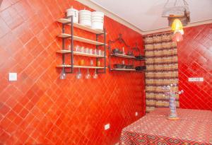 uma parede vermelha com prateleiras e uma mesa num quarto em Jet Villas Entebbe ( JVE ) em Entebbe