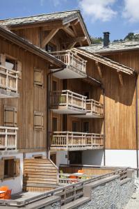 モンジェネヴルにあるCGH Résidences & Spas Le Chalet des Dolinesのバルコニーとオレンジの椅子が備わる大きな木造の建物です。