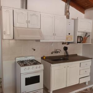 a white kitchen with a stove and a sink at Alojamiento Shanti in Vista Flores