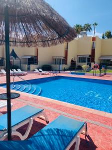 a swimming pool with two chairs and an umbrella at El cortijo Bungalow Playa las Americas in Playa de las Americas