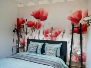 a bedroom with a bed with red flowers on the wall at Bed & Breakfast Udens Buiten in Veghel