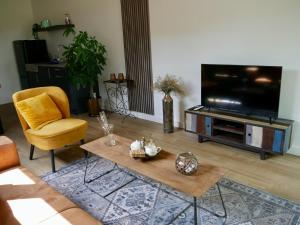 a living room with a television and a coffee table at Bed & Breakfast Udens Buiten in Veghel