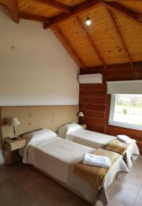 2 camas en una habitación con techos de madera en El Hierro Apart en Villa Ciudad Parque